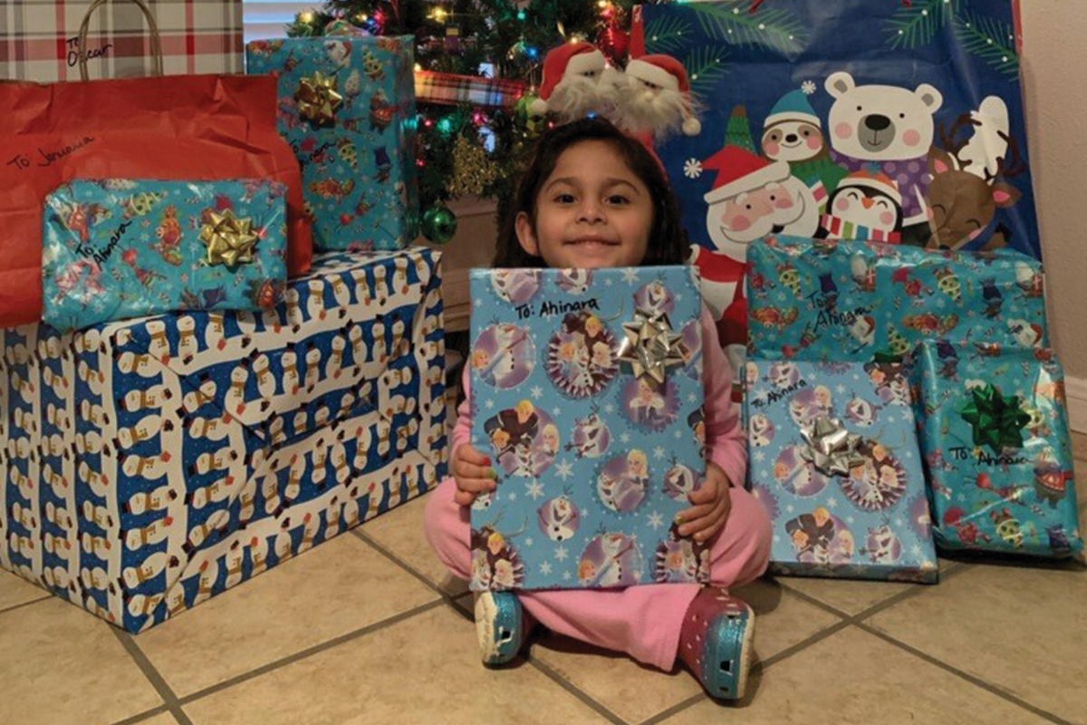 Adopt-A-Family participant with donated warpped gifts